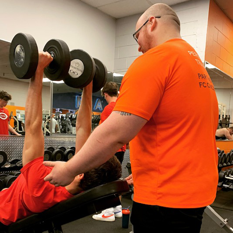 Miami Athletic Club personal trainer spotting a man using weights