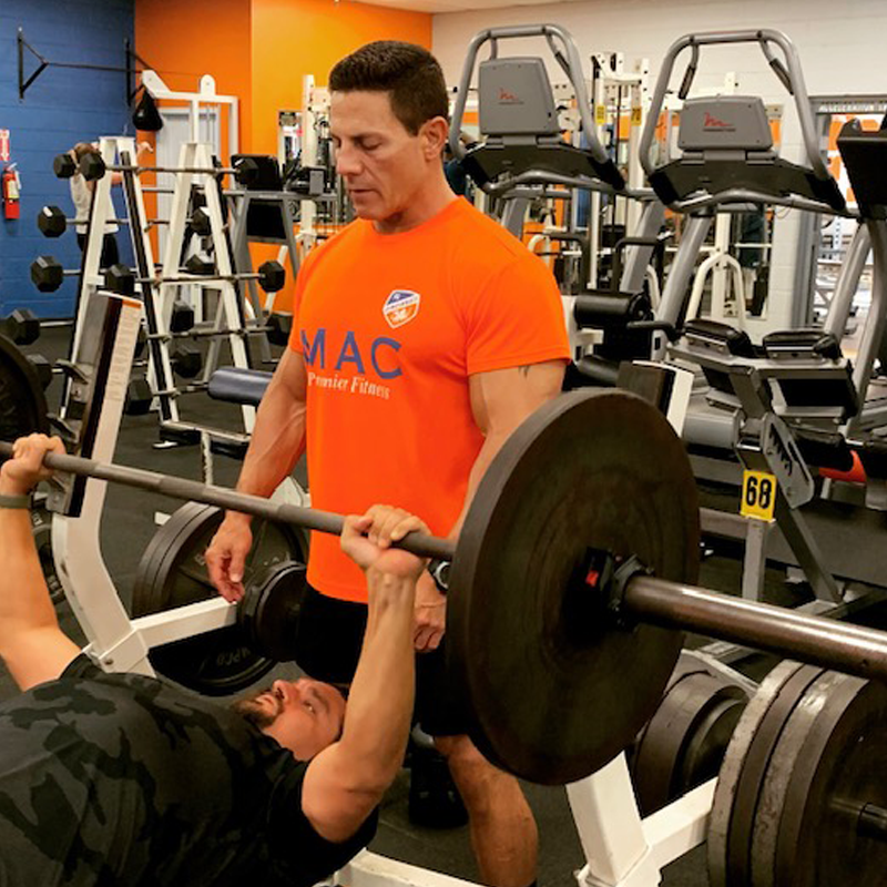 Miami Athletic Club personal trainer spotting a man using weights